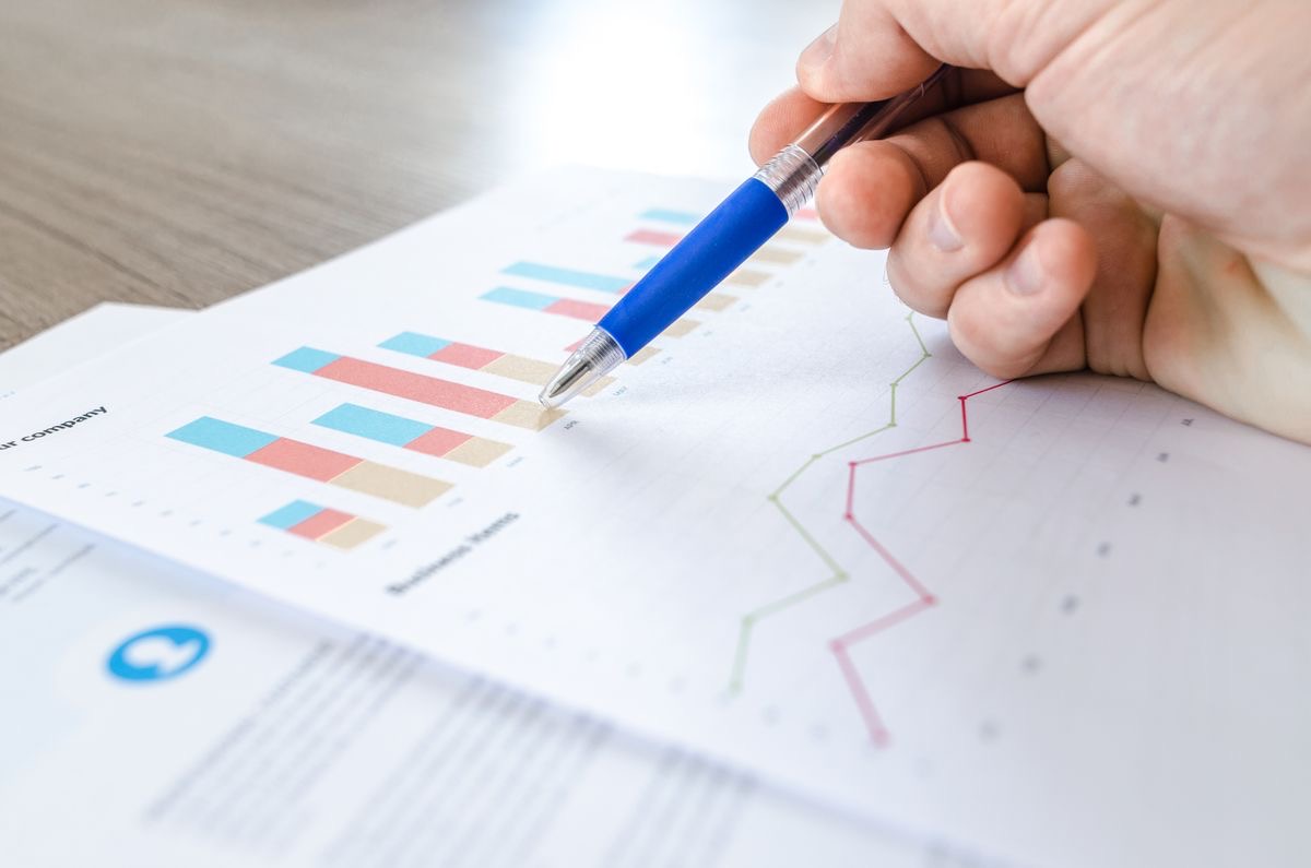 Analytics charts on a printed report with a pen tracking the trend
